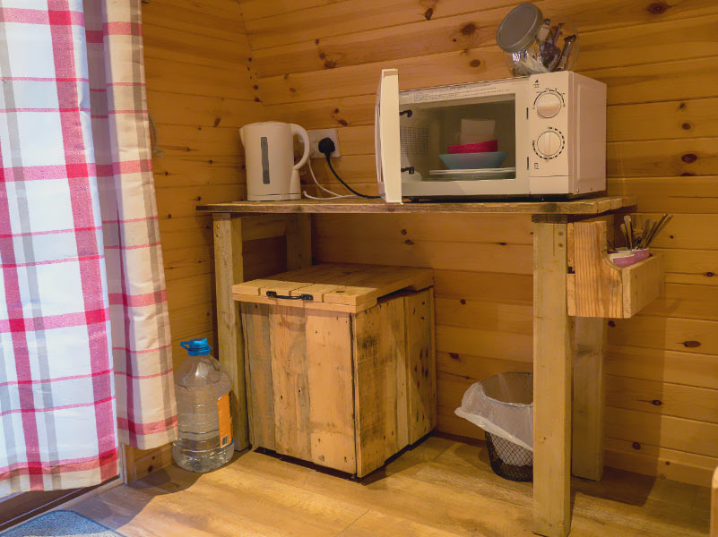 Glamping Pod kitchenette with bin, water carrier, kettle and microwave