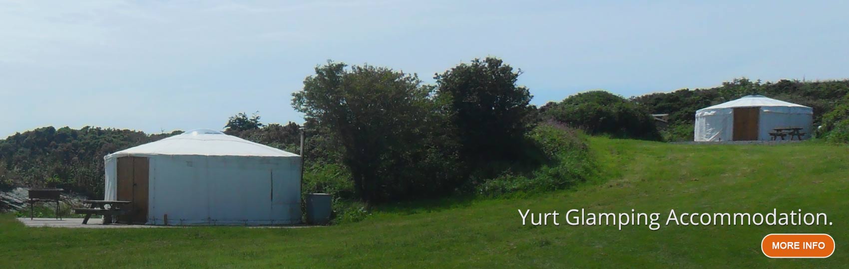 Two glamping Yuts at the base of a hill the the summer sun