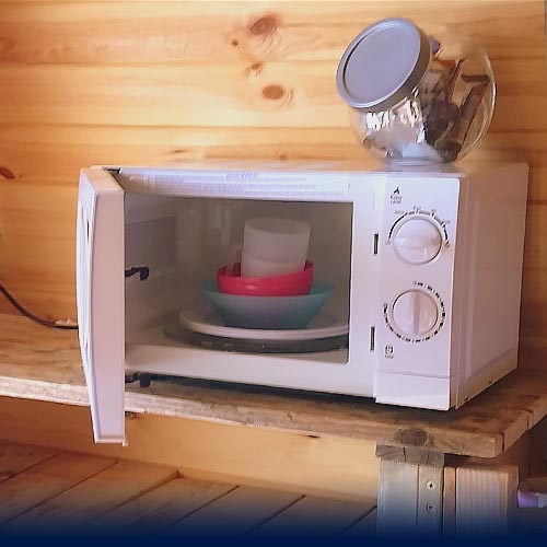 Microwave with kitchen crockery and utensils inside